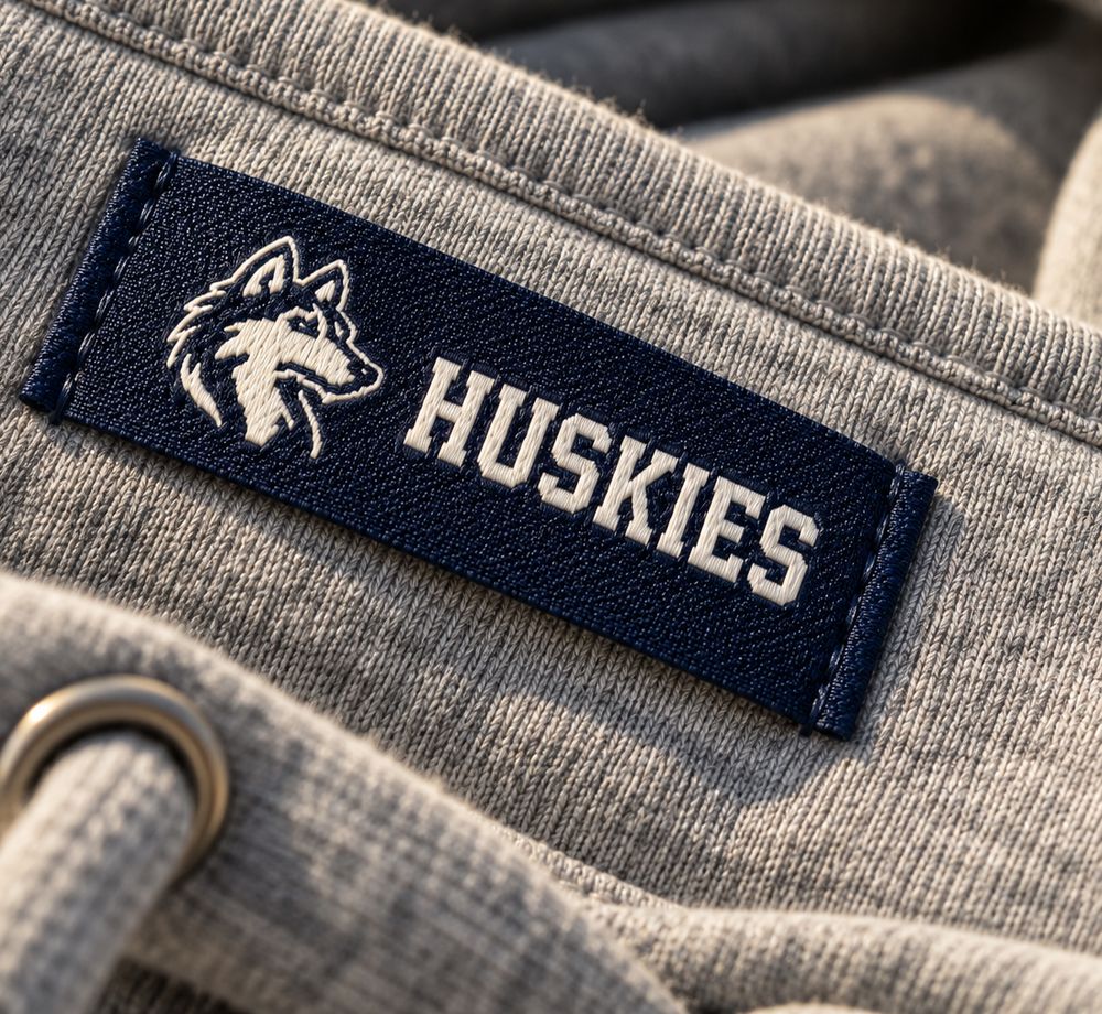 Navy woven label with a husky logo sewn onto a grey hoodie