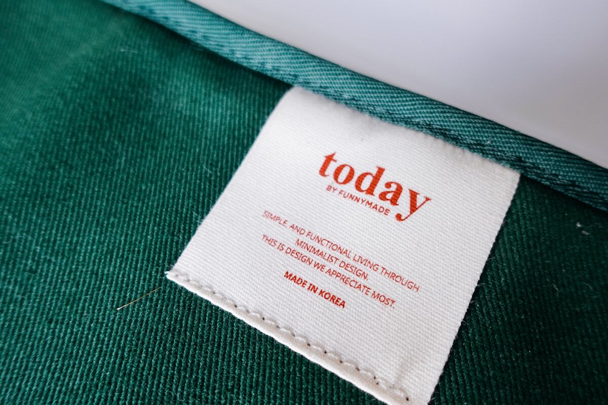 White printed fabric label stitched onto green twill