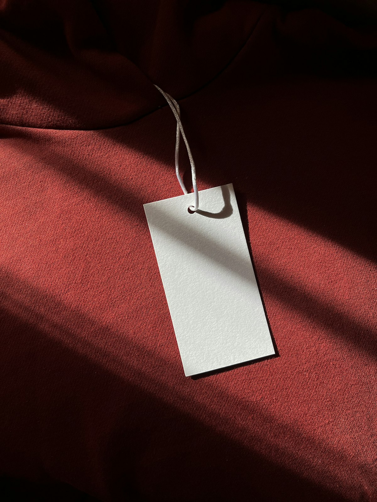 White hang tag with cord on a rust-red hoodie
