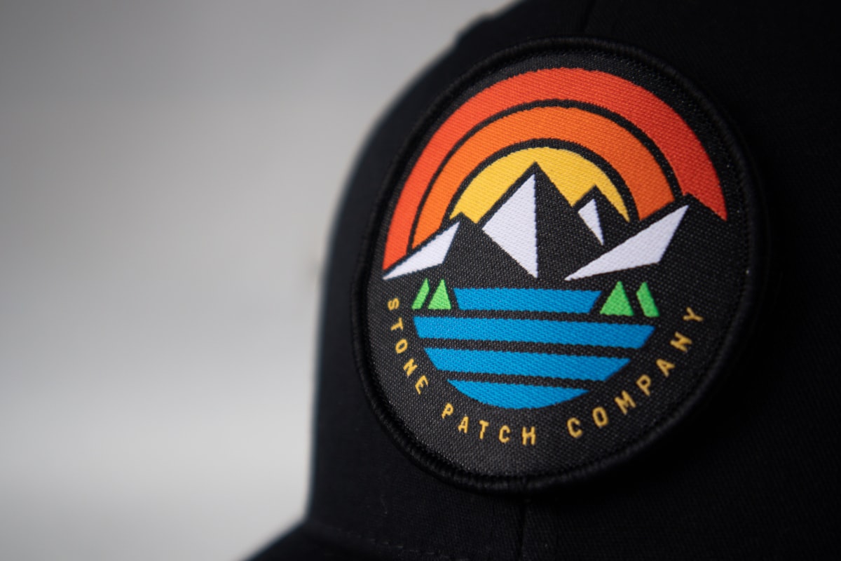 Round woven patch with mountain logo on a black cap