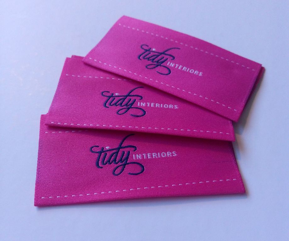 Pink woven labels with script logo and stitch border