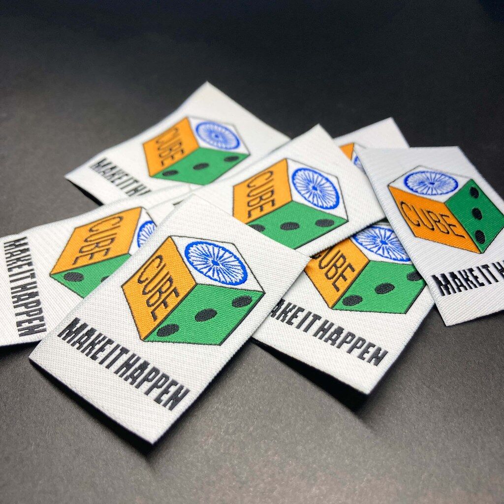 Stack of white woven labels with a multicolour cube logo