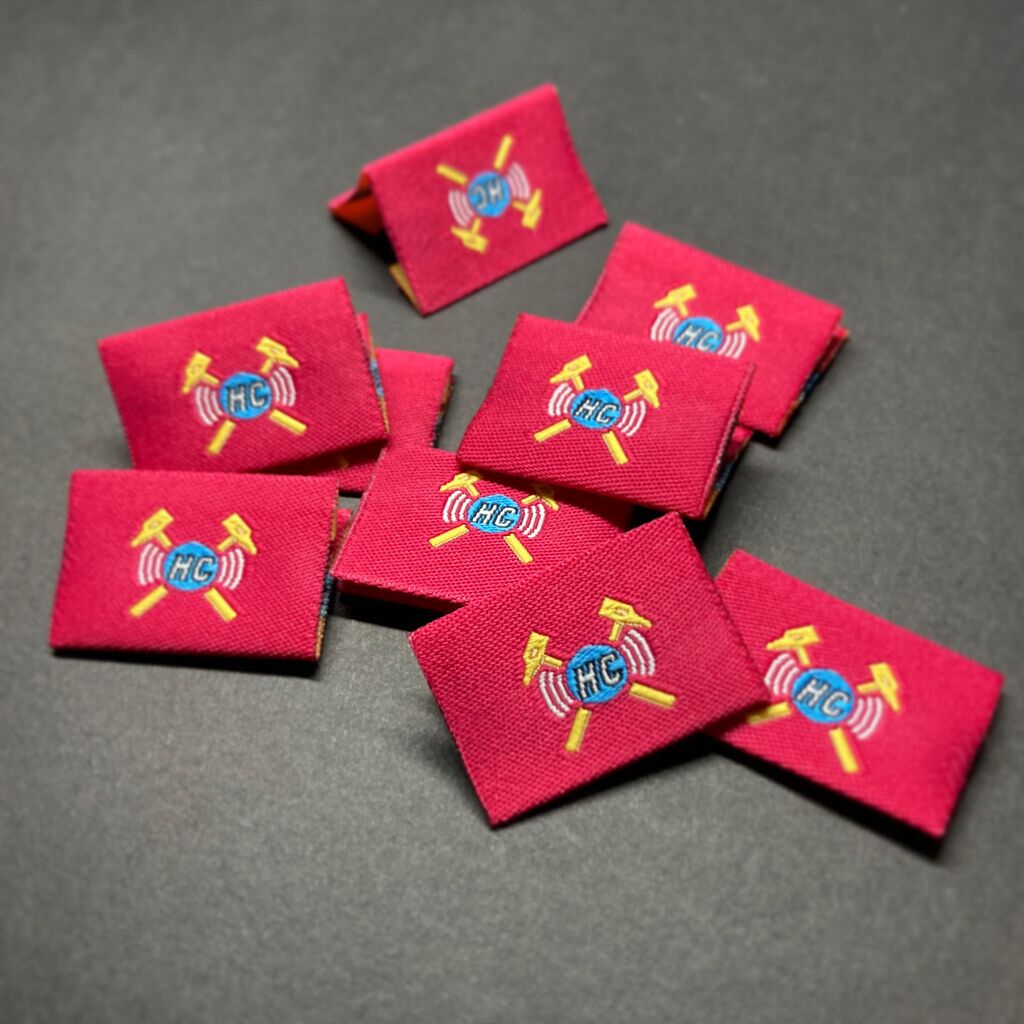 Red center-fold woven labels with a detailed crest logo